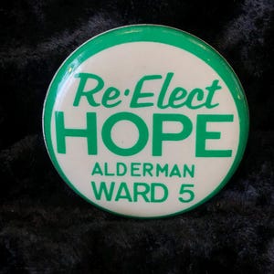 Könnte beinhalten: Ein weißer und grüner Knopf mit dem Text "Re-Elect HOPE Alderman Ward 5".