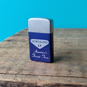 May include: A blue lighter with a silver top and a white label that says "Seiberling America's Finest Tires".