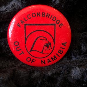 Könnte beinhalten: Runder roter Knopf mit schwarzem Text und einer schwarzen Silhouette eines Falken. Der Text lautet "Falconbridge Out of Namibia".