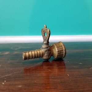May include: A brass faucet spout with intricate details and a decorative design. The spout is a vintage style and has a worn finish.