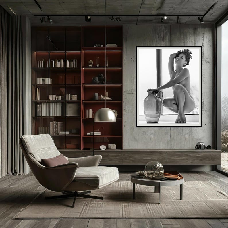 Peut inclure: Une photographie en noir et blanc d'une femme assise sur un rebord de fen&ecirc;tre avec une grande jarre en c&eacute;ramique. La femme est nue et ses cheveux sont tir&eacute;s en arri&egrave;re. La photographie est encadr&eacute;e et accroch&eacute;e &agrave; un mur gris.