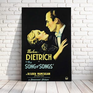 May include: A vintage movie poster for the film "The Song of Songs" starring Marlene Dietrich. The poster features a black and white image of Dietrich and a man looking at each other. The text on the poster is in yellow and white.