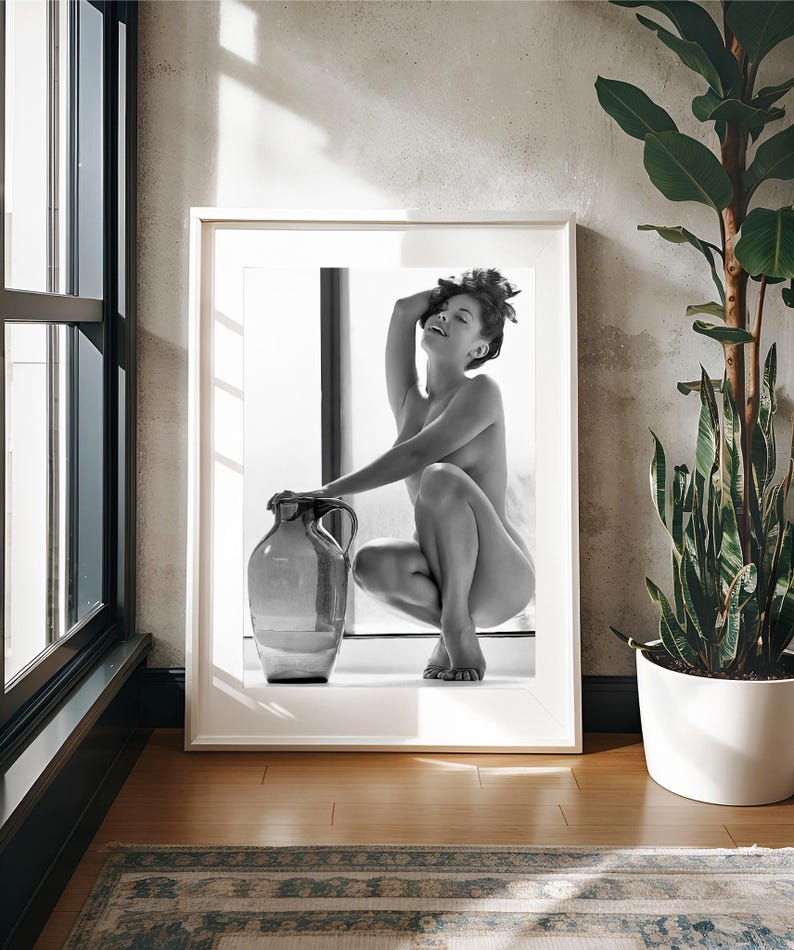 Peut inclure: Une photographie en noir et blanc d'une personne assise avec un grand pot en verre transparent. La personne est assise sur une surface blanche avec une fen&ecirc;tre derri&egrave;re elle.