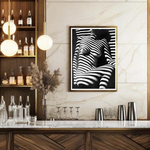 May include: Black and white photo of a person with light and shadow stripes, framed in a gold frame.