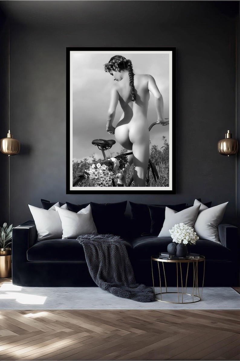 May include: A black and white photograph of a person standing behind a bicycle. The person is nude and has a flower crown in their hair. The bicycle is in the background and is partially obscured by flowers.