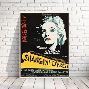 May include: A vintage movie poster for the film "Shanghai Express" starring Marlene Dietrich. The poster features a black and white image of Dietrich with a red lip and a dramatic expression. The title of the film is in yellow and red lettering. The poster also includes the text "Paramount Presents" and "C'est un film Paramount".