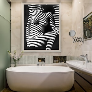 May include: A white bathtub with chrome fixtures in a bathroom with a black and white photo of a person in a striped pattern hanging on the wall.