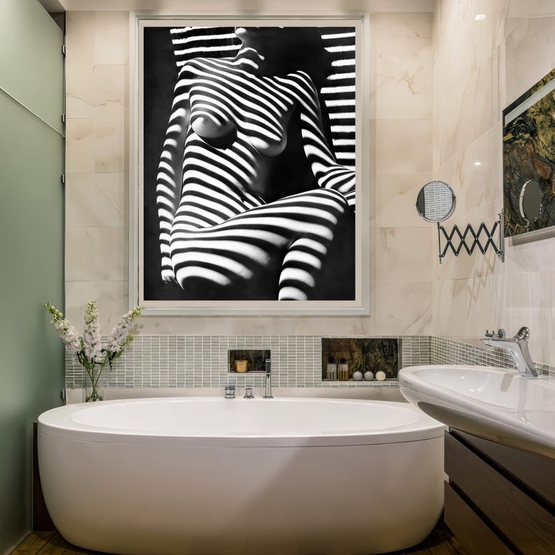 May include: A white bathtub with chrome fixtures in a bathroom with a black and white photo of a person in a striped pattern hanging on the wall.