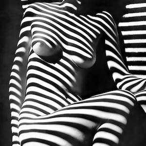 May include: Black and white photograph of a person's body with light and shadow patterns created by a window blind.