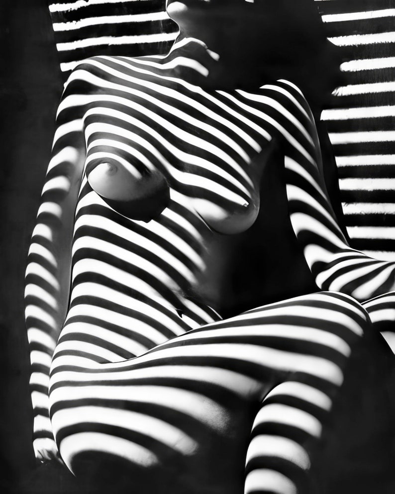 May include: Black and white photograph of a person's body with light and shadow patterns created by a window blind.