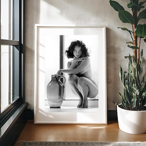 May include: A black and white photograph of a woman sitting on a windowsill with a large ceramic jug. The woman is looking directly at the camera with a serious expression.