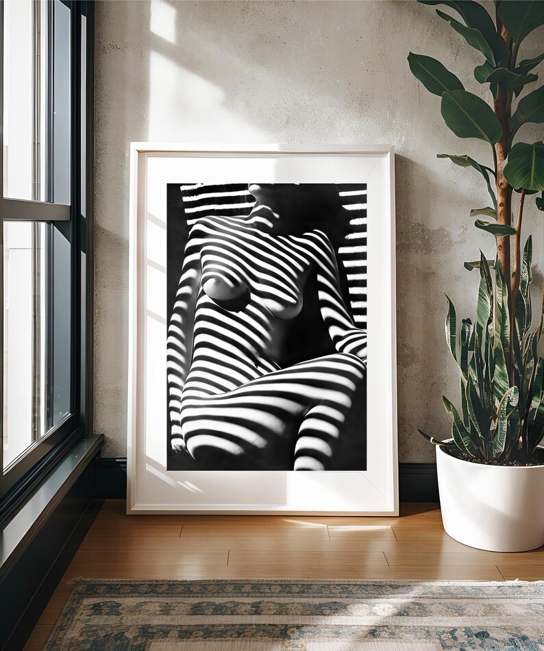 May include: Black and white photograph of a person's torso and legs, with light and shadow creating a striped pattern.