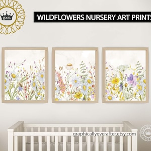 May include: Three watercolour prints of wildflowers in shades of yellow, purple, and white. The prints are framed in a light wood frame and are hung on a white wall. The prints are part of a nursery decor set.