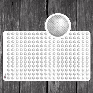 May include: A white sticker sheet with numerous small, textured, gray golf ball designs. A larger golf ball graphic is featured in the upper right corner. The sticker sheet is on a dark wood grain background.