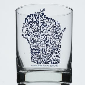 Könnte beinhalten: Ein klares Glas mit einer blauen Grafik des Bundesstaates Wisconsin. Die Grafik ist mit den Namen von Städten und Wahrzeichen von Wisconsin gefüllt. Die Worte "BIG FOOT BEACH" befinden sich am Boden des Glases.
