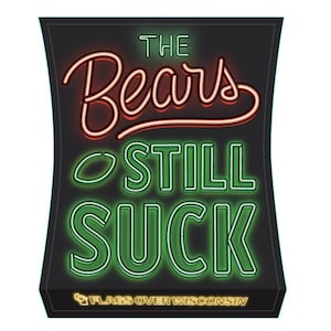May include: A black sign with neon green and red text that reads "The Bears Still Suck" with the words "Flags Over Wisconsin" in yellow at the bottom.