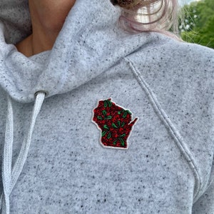 May include: A gray hooded sweatshirt with a red and green embroidered patch of the state of Wisconsin.