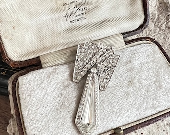 May include: A vintage silver brooch with a geometric design and clear rhinestones. The brooch is in a velvet-lined box with the inscription "Goldsmith,  Hennesse & Hardy, 41&43 London St, Norwich."