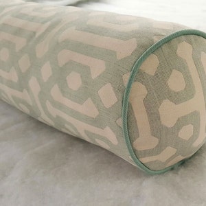 May include: A light green and white patterned bolster pillow with a light green piping around the edge.