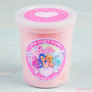 May include: A pink plastic container filled with pink cotton candy. The container has a pink lid with a heart design. A large pink label on the front reads "Pink Fairy Floss Barbie Cotton Candy" with an image of two cartoon women.