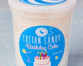 May include: A clear plastic container filled with white cotton candy. The container has a blue and white swirl design lid and a blue and white label that says "Cotton Candy Birthday Cake" with a picture of a birthday cake with candles.