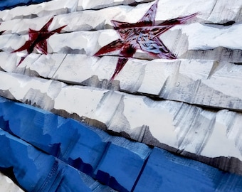 May include: A wooden wall art piece depicting the Chicago flag. The flag is made of wood planks painted white, blue, and red. The red stars are carved into the wood and painted red.