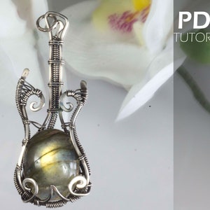 May include: A handcrafted silver wire guitar pendant with a central oval-shaped labradorite stone. The pendant features intricate wire wrapping and detailing, with the text "PDF TUTORIAL" in the upper right corner.