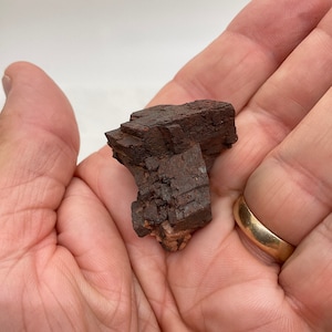 May include: A close-up of a dark brown, rough-textured mineral specimen. The mineral has a layered, blocky structure and appears to be a natural crystal.