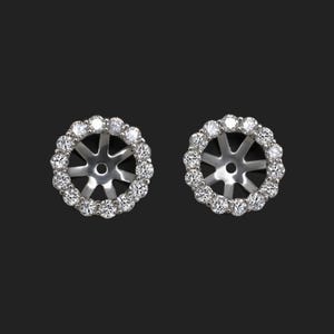 May include: A pair of silver earring settings with a round halo of small diamonds.