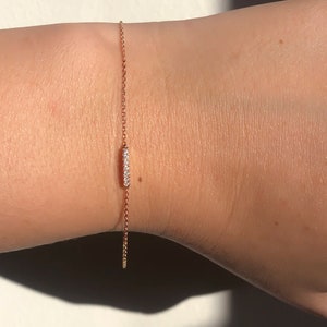 May include: A delicate rose gold chain bracelet with a small bar set with clear diamonds.