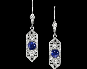 May include: A pair of silver dangle earrings with a blue gemstone and diamond accents.