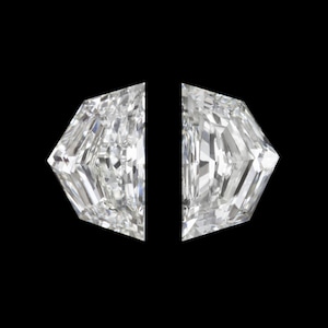 May include: Two white, brilliant-cut diamonds with a distinctive geometric form. Each stone features a multifaceted surface, reflecting light. The diamonds are set against a black background, accentuating their clarity and sparkle.