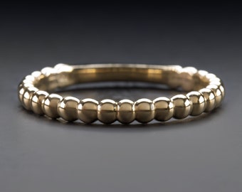 May include: A simple gold band ring with a beaded design. The ring is made of a smooth, polished metal and has a classic, timeless look.