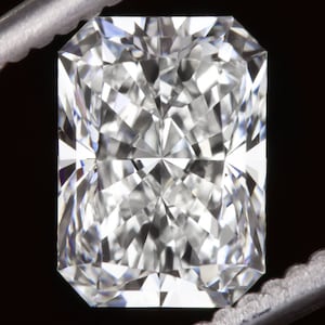 May include: A large, clear, rectangular-shaped diamond with many facets.