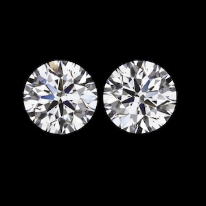 May include: Two round, brilliant cut diamonds, set against a black background.