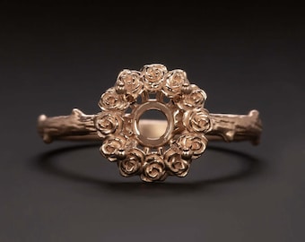 May include: A rose gold ring setting with a delicate branch design and a center stone setting surrounded by a ring of roses.
