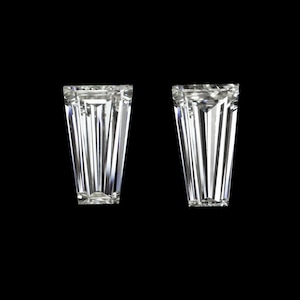 Pode incluir: Dois diamantes transparentes, facetados, de forma retangular com uma parte superior pontiaguda e uma base quadrada.