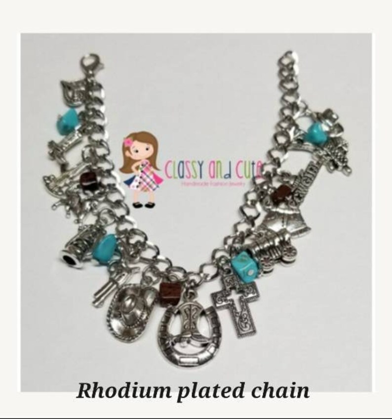 May include: A silver charm bracelet with a rhodium plated chain and various charms, including a horseshoe, a cross, a cowboy boot, and a cowboy hat. The charms are accented with turquoise blue beads.