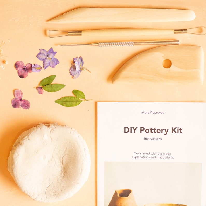 K&ouml;nnte beinhalten: Ein DIY-T&ouml;pferset mit einem Block wei&szlig;en Tons, Holzwerkzeugen und Anleitungen. Das Set enth&auml;lt getrocknete Blumen zur Dekoration.