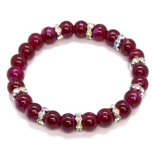 May include: A burgundy glass bead bracelet with silver accents. Each bead has a sparkly, iridescent finish.