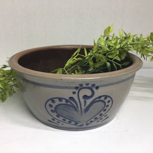 May include: A gray ceramic bowl with a blue and white floral design. The bowl is filled with green leafy plants.