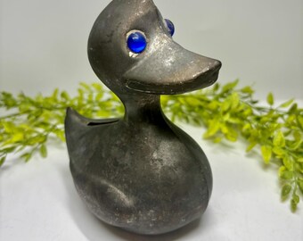 Salvadanaio vintage a forma di anatra in peltro con occhi di vetro.
