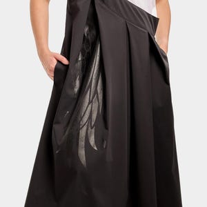 Puede incluir: Vestido negro sin mangas con un dise&ntilde;o de ala y el texto "Stella McCartney" en la tira. El vestido tiene una falda plisada y un corte holgado.