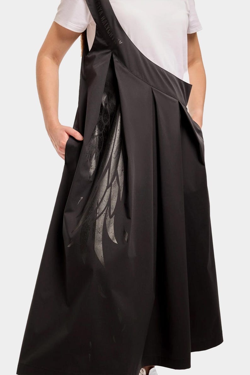 Puede incluir: Vestido negro sin mangas con un dise&ntilde;o de ala y el texto "Stella McCartney" en la tira. El vestido tiene una falda plisada y un corte holgado.