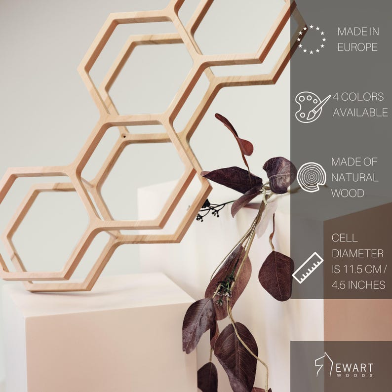 May include: A light-colored wooden honeycomb wall shelf with three hexagonal cells. Text on the right indicates it is made in Europe, available in 4 colors, made of natural wood, and has a cell diameter of 4.5 inches. The brand is Ewart Woods.