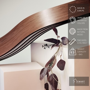 May include: A wooden, wavy design element in shades of brown. The product is made from natural wood and available in two sizes. The weight capacity is approximately 5 kg. The text on the image says "Made in Europe" and "Available in 4 wood colors."