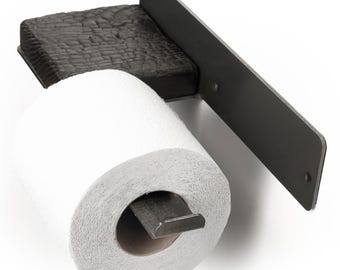 May include: Black metal toilet paper holder with a burnt wood base. The holder is mounted to a wall and has a metal bar that holds the toilet paper roll.
