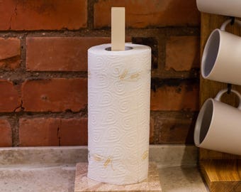 Peut inclure: Un rouleau de papier essuie-tout blanc avec un motif de libellule sur un comptoir en pierre beige. Le rouleau est sur un support en bois avec un cheville en bois.