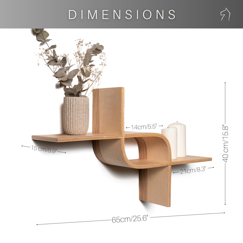 May include: A light-colored wooden wall shelf with a unique, curved design. The shelf is 25.6 inches wide and 15.8 inches high. It features two shelves and a vertical support. A vase with dried flowers and two white candles are displayed on the shelf.