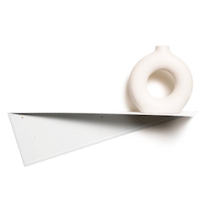 Puede incluir: Un jarrón de cerámica blanco con una abertura circular se coloca sobre una estantería triangular blanca con una superficie texturizada.